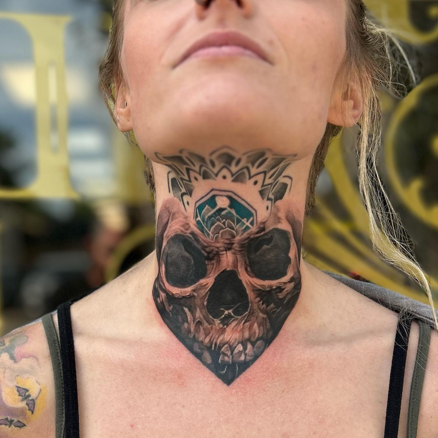 Woman with skull neck tattoo and a decorative crown design.