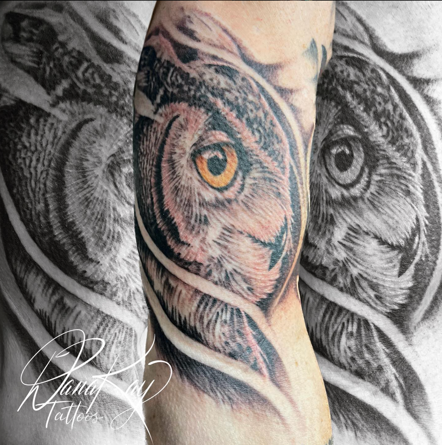 Tattoo of an owl's face on an arm. The owl's eye is yellow, with detailed fur and feathers in black and grey.