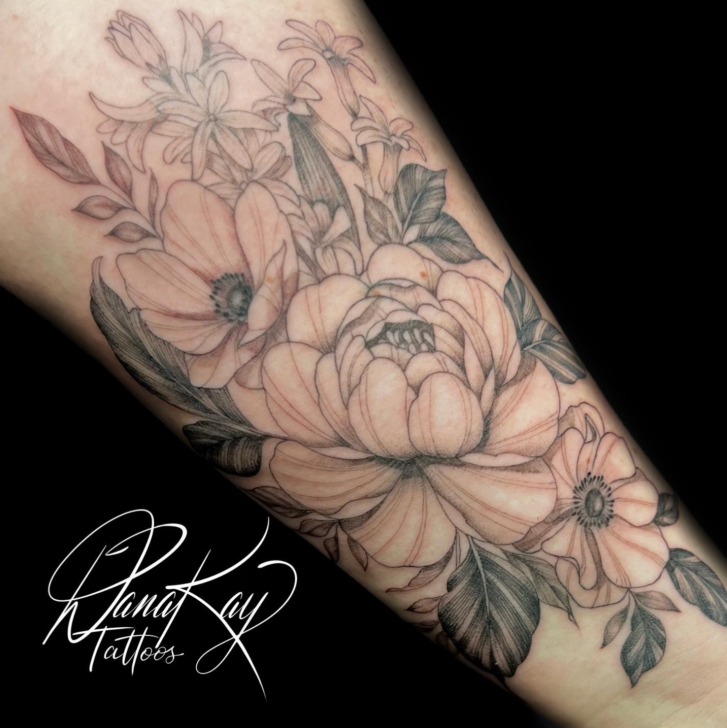Black and white floral tattoo on arm, with peony and other flowers.