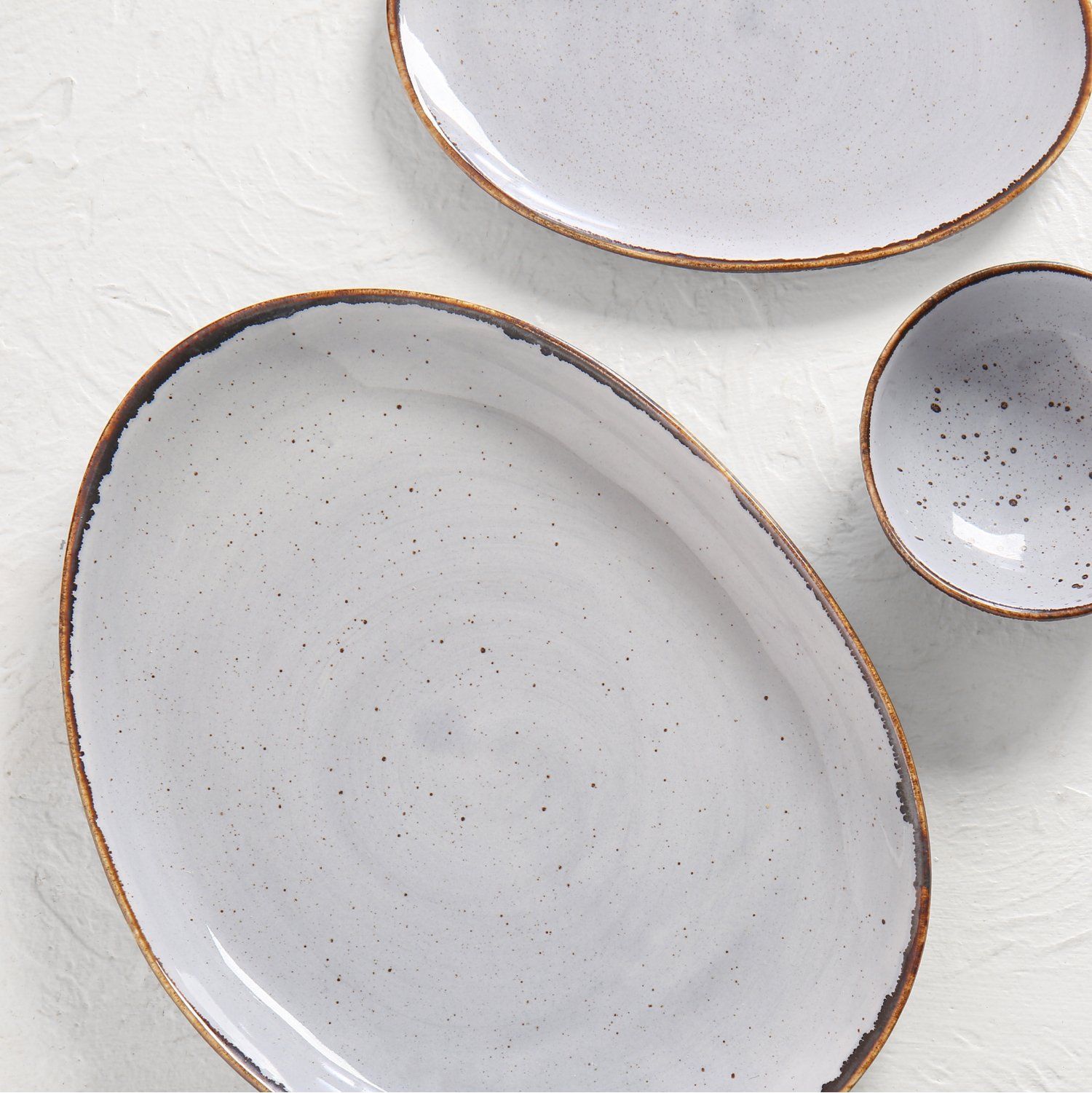 Oval, gray speckled ceramic plate with a gold rim.