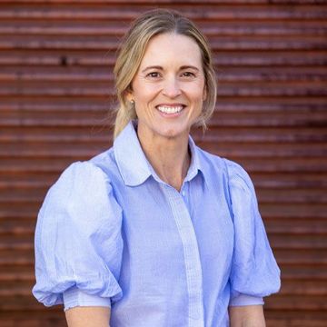 Brooke from Homestead Agribusiness in a light blue shirt standing before a brown wooden wall