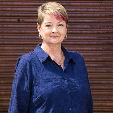 Kathy from Homestead Agribusiness  in a blue shirt against a wooden wall background