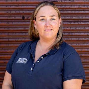 Sunshine from Homestead Agribusiness  in a blue shirt against a wooden wall background