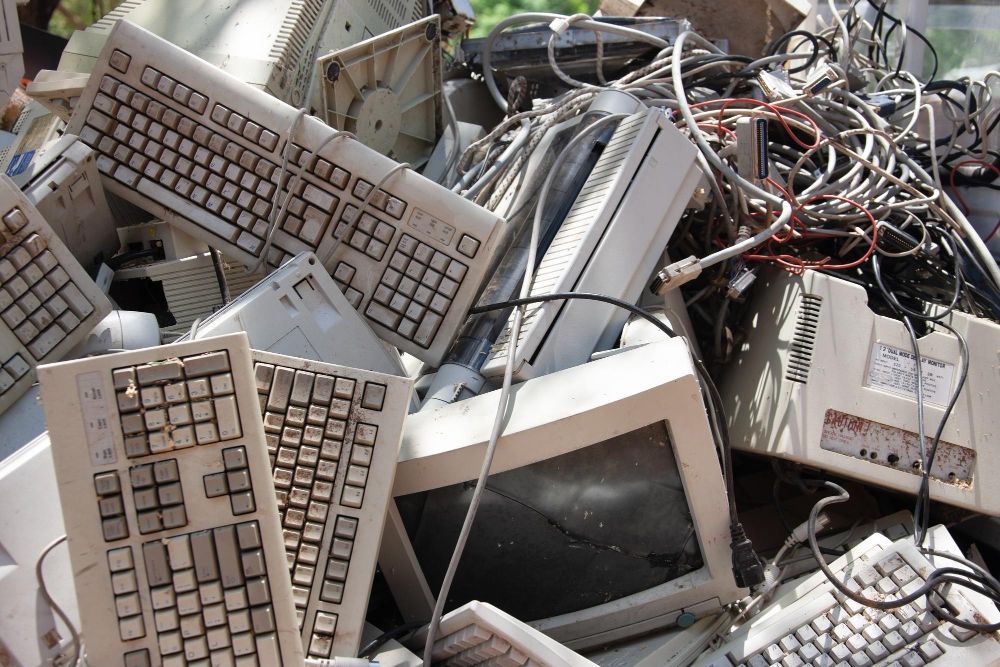 A pile of old computer equipment including keyboards and monitors