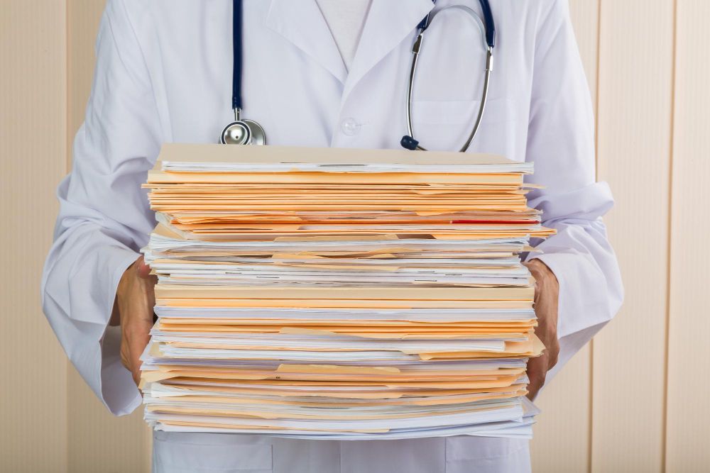 A doctor is holding a stack of medical records in his hands.