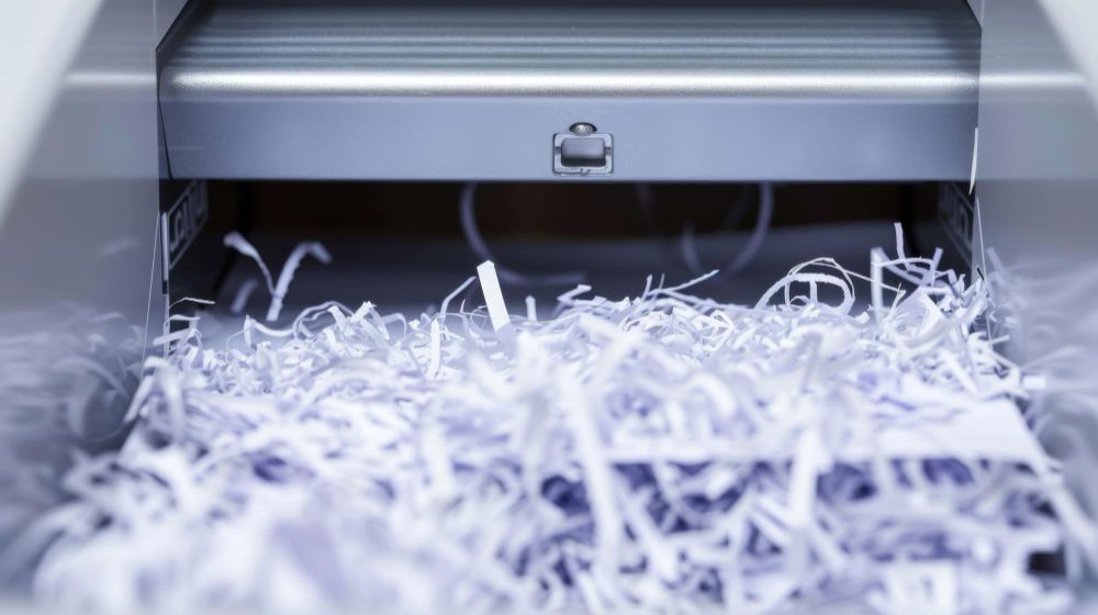 A pile of shredded paper is coming out of a shredding machine.
