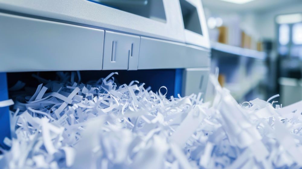 A pile of shredded paper is coming out of a shredding machine.