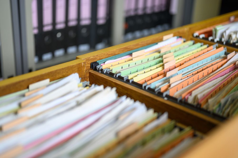 A wooden drawer filled with lots of papers and binders.