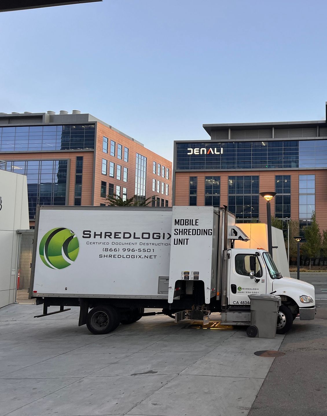 A shredding truck is parked in front of a building