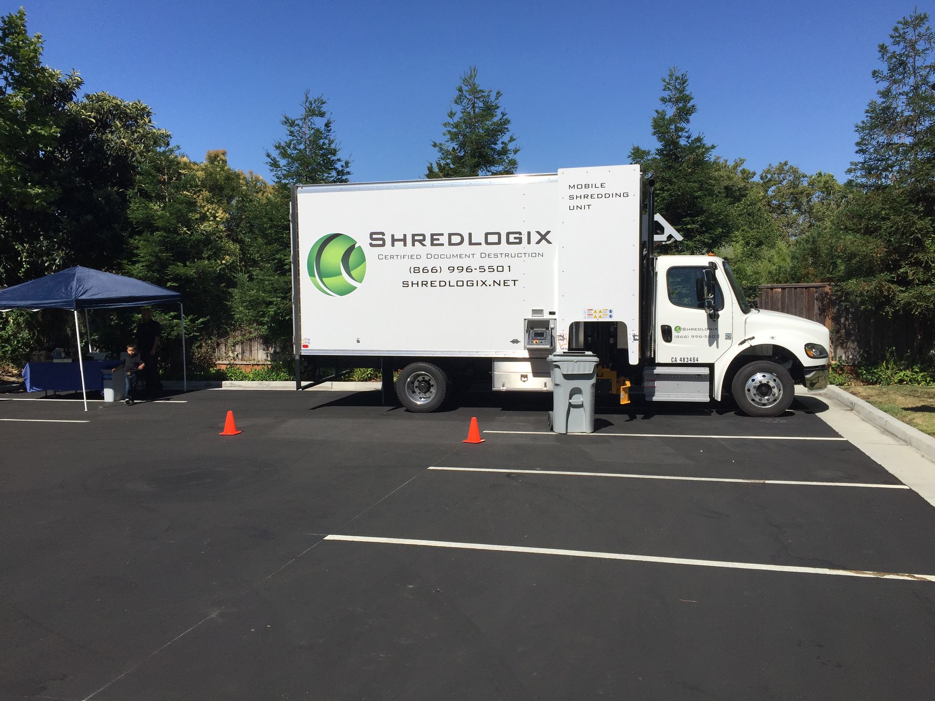 A white shredlogix truck is parked in a parking lot
