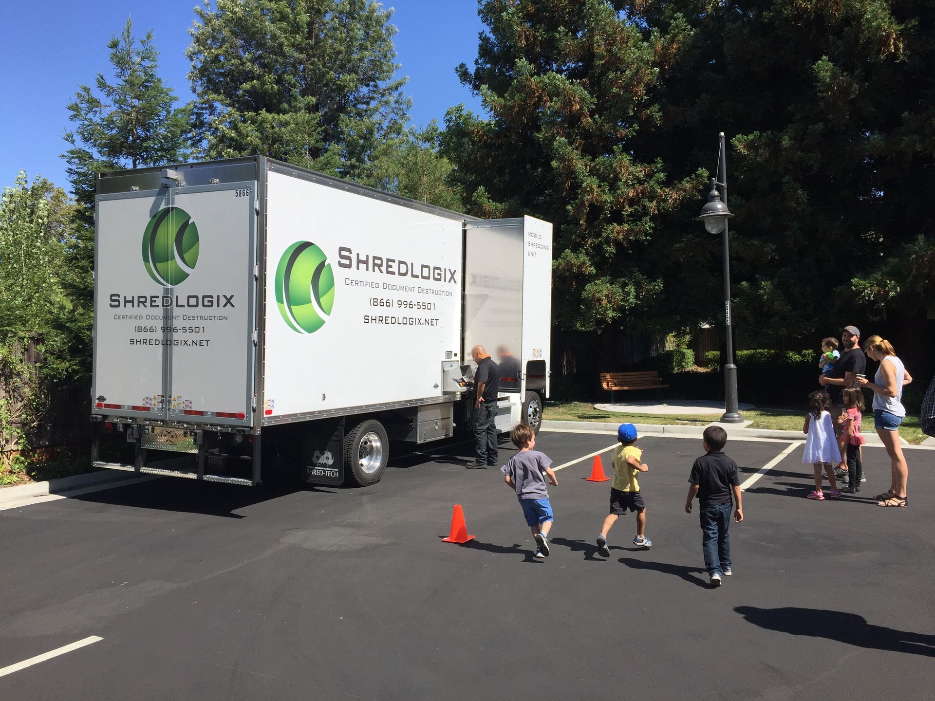 A group of children are playing in front of a shredding truck.