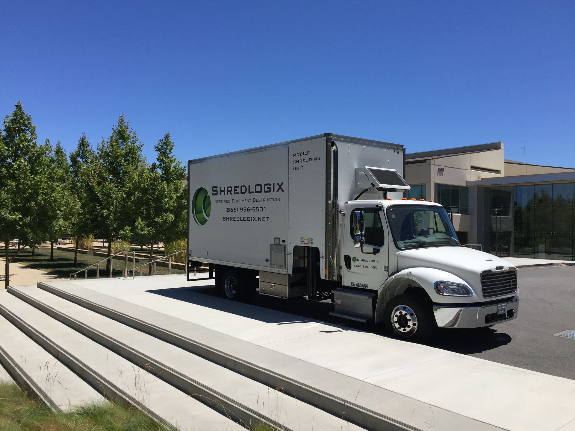 A white truck is parked on the side of the road in front of a building.