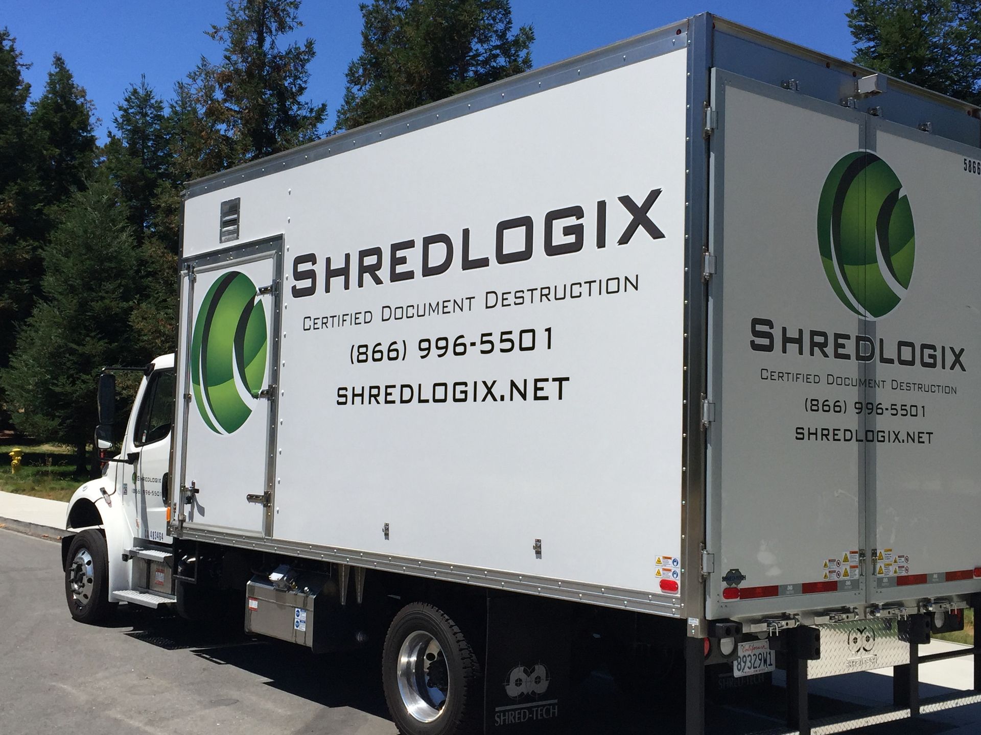 A white shredlogix truck is parked on the side of the road