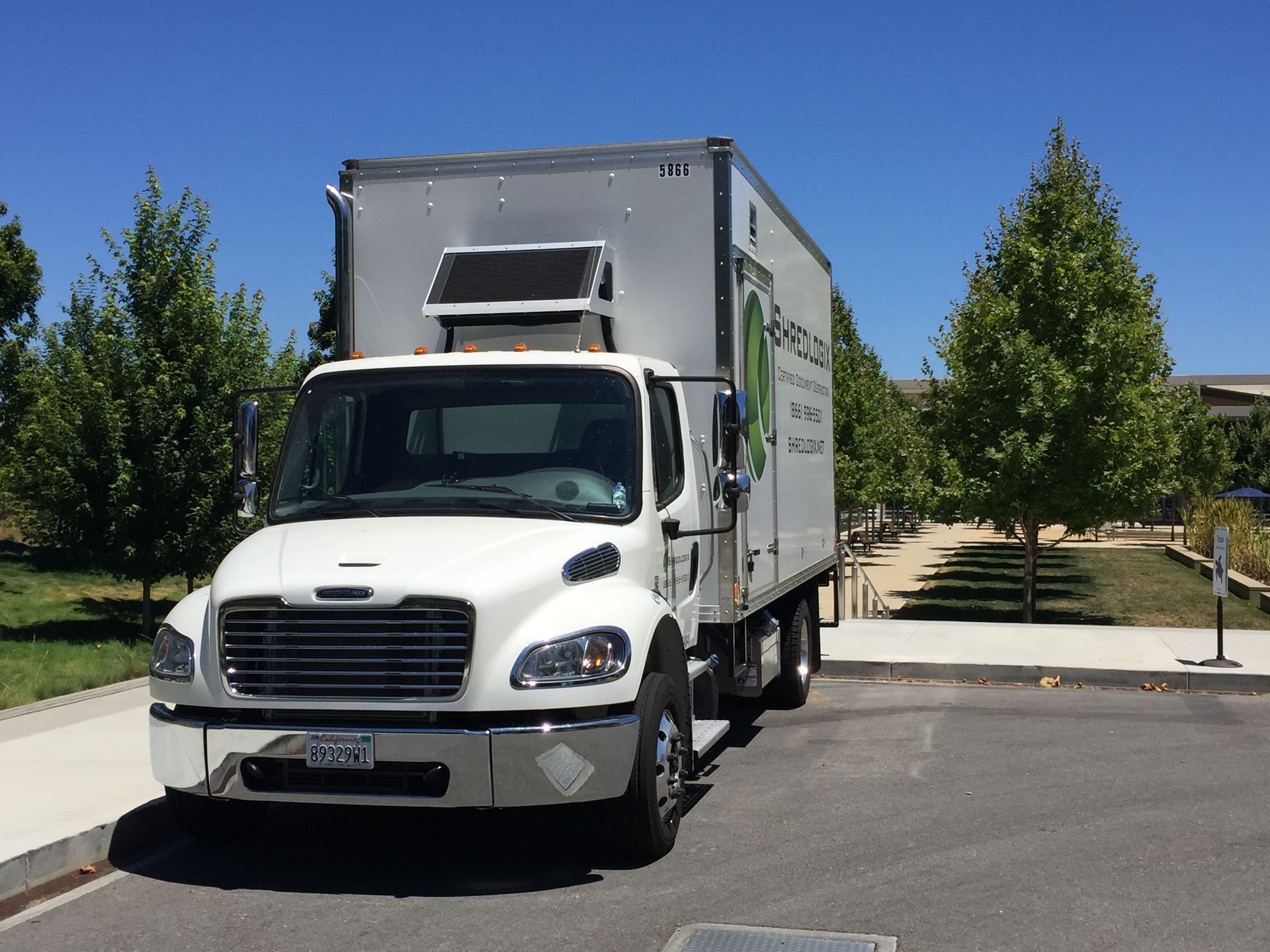 A white truck is parked in a parking lot with trees in the background