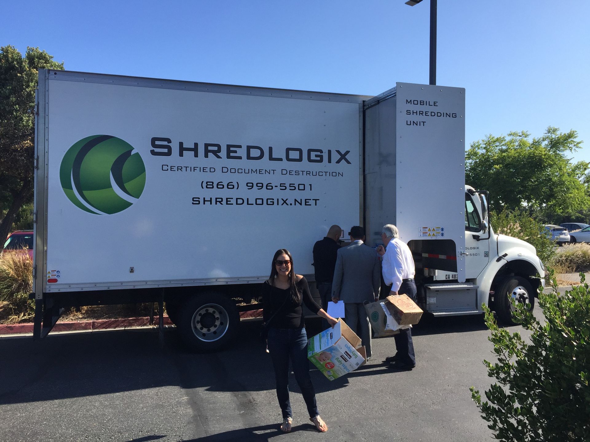 A woman is standing in front of a shredlogix truck