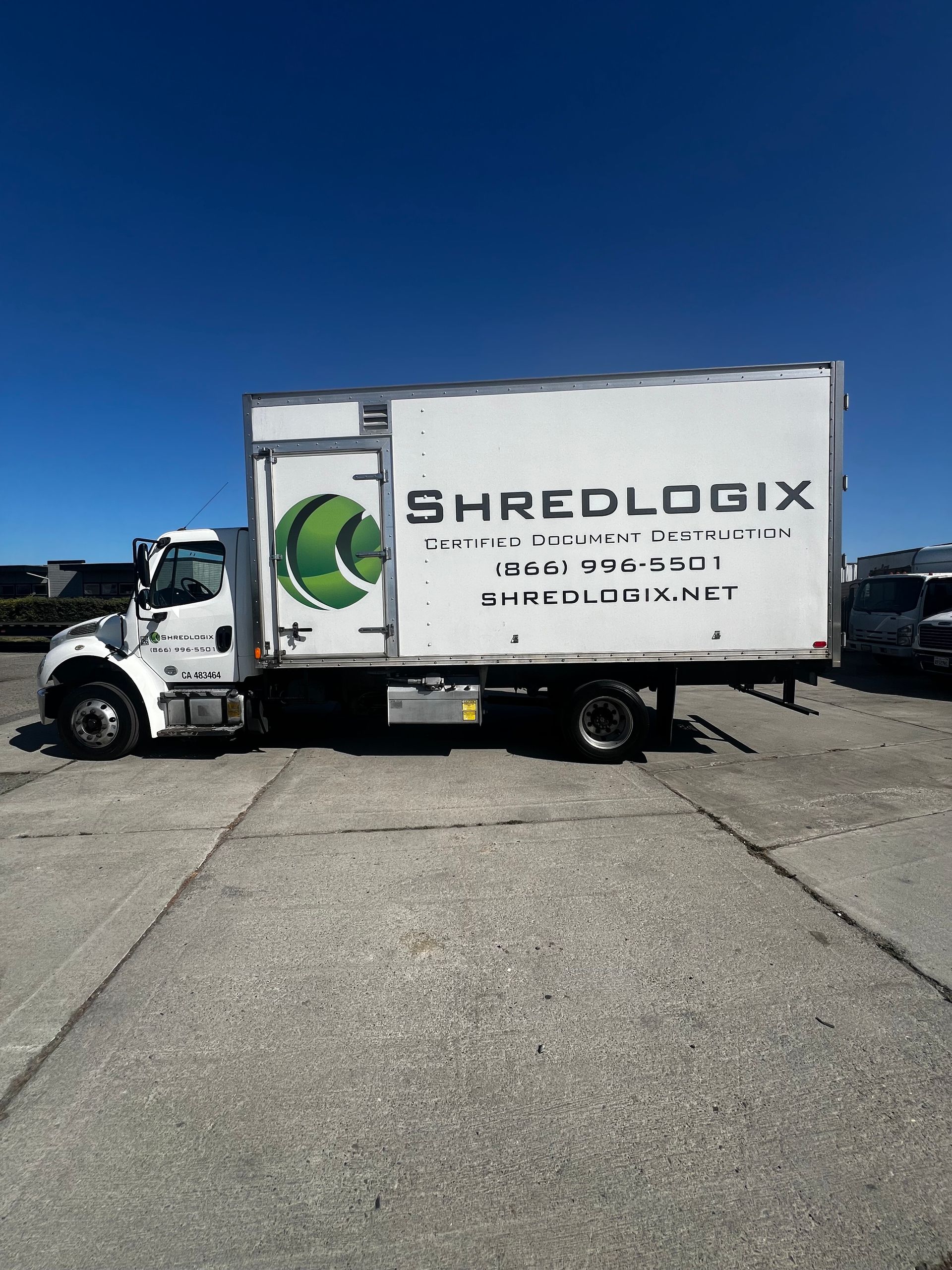A white shredlogix truck is parked in a parking lot.