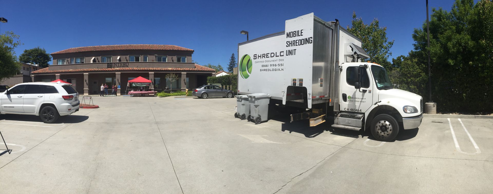 A white truck is parked in a parking lot in front of a building.