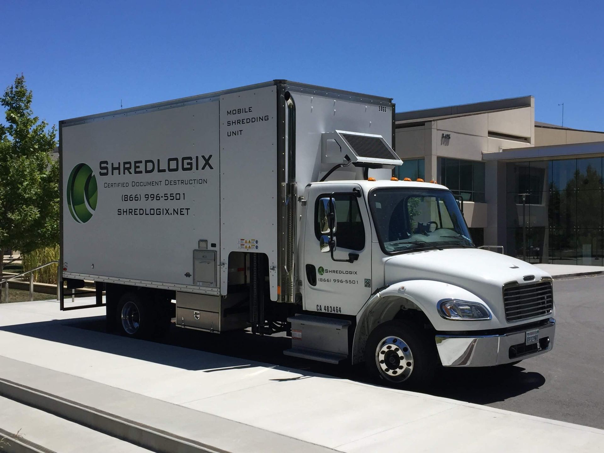 A white shredlogix truck is parked on the side of the road.