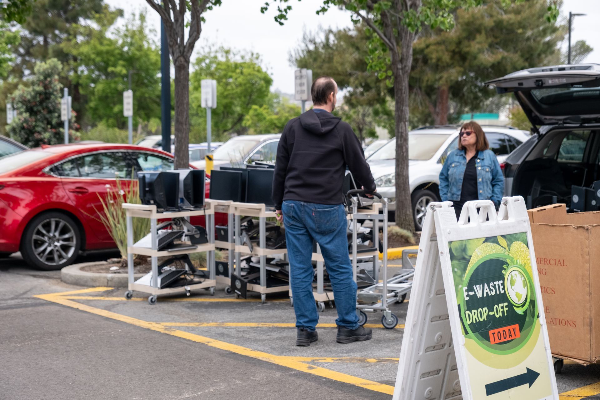 A man and a woman are standing in a parking lot next to a sign.