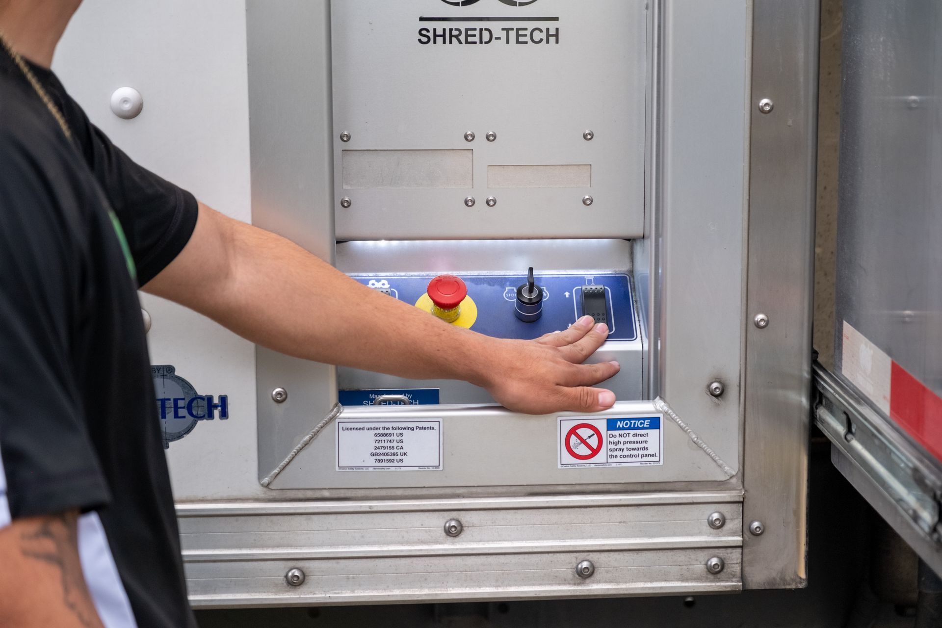 A man is pushing a button on a machine that says shred tech