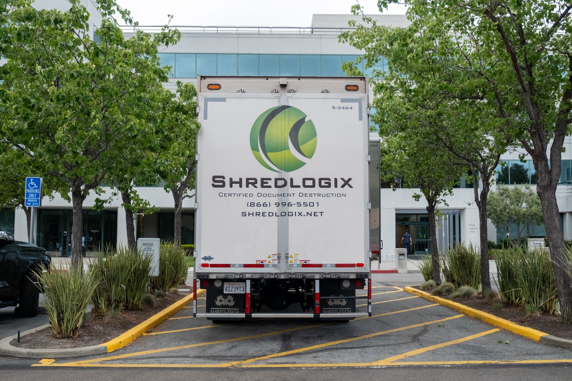 A white shredlogix truck is parked in a parking lot
