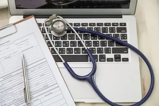 Stethoscope and medical form on laptop showing legal shredding requirements for healthcare.