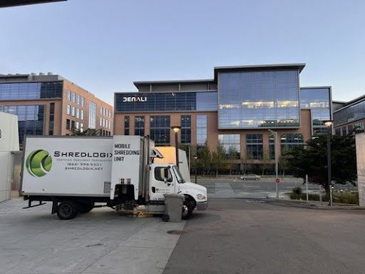 Shredlogix mobile truck parked outside a corporate building providing scheduled shredding service for document disposal.