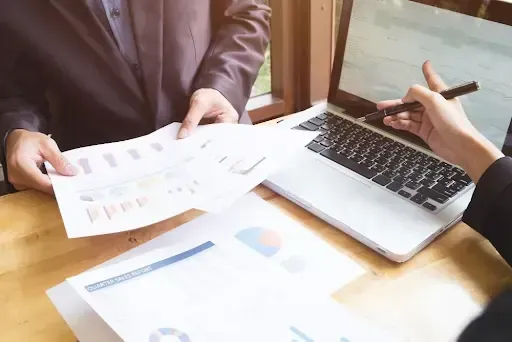  Two professionals reviewing printed charts and graphs, discussing a shredding schedule for finance in Santa Clara.