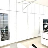 Bright white kitchen cabinets with built-in appliances and a pale floor in a modern interior