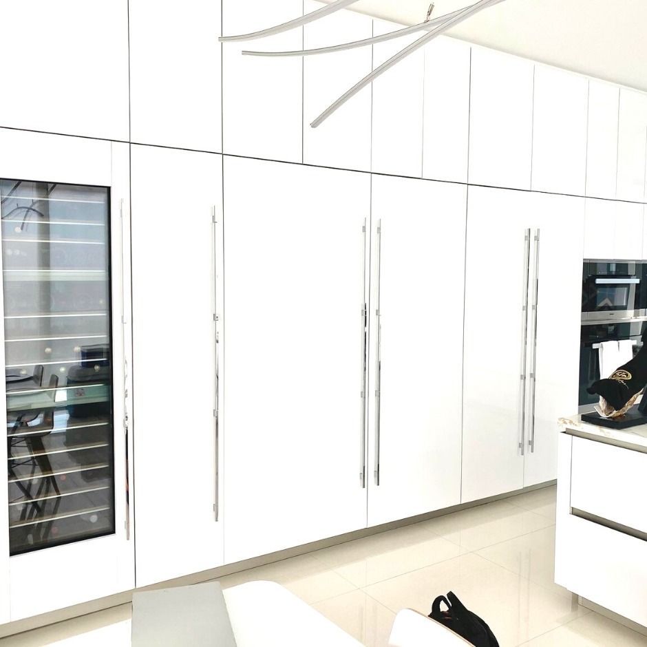 Bright white kitchen cabinets with built-in appliances and a pale floor in a modern interior