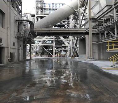 Industrial facility interior with wet concrete floor, metal catwalks, and large overhead ducts