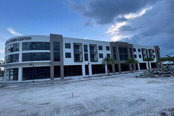 Modern two-story commercial building under construction with piles of dirt in front at dusk
