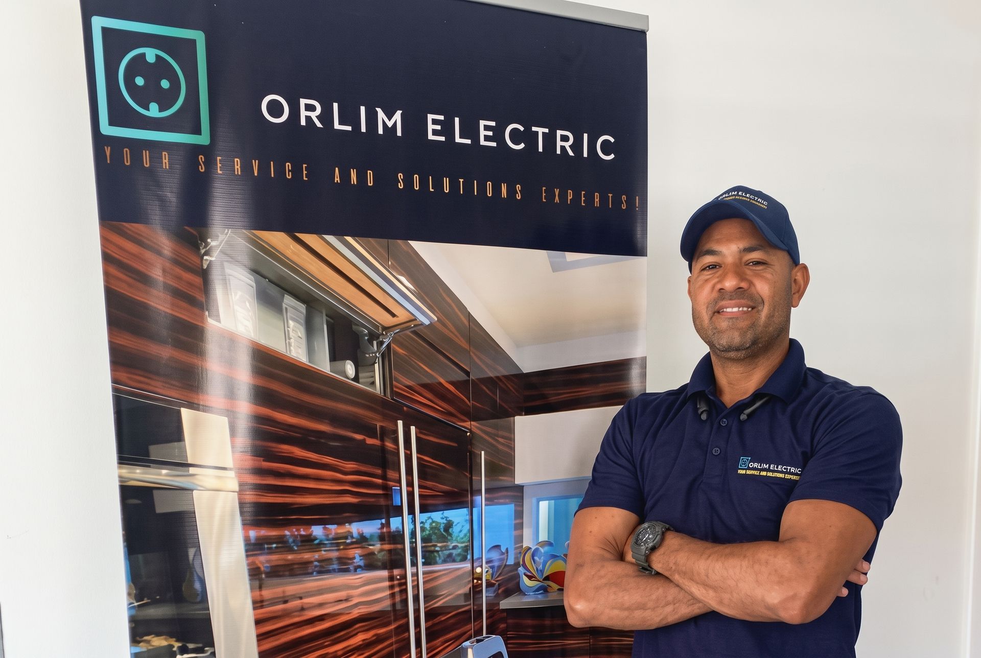 Man standing with arms crossed beside an ORIM Electric banner in a showroom-like setting