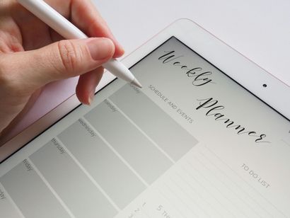 Hand with stylus writing on a digital weekly planner.