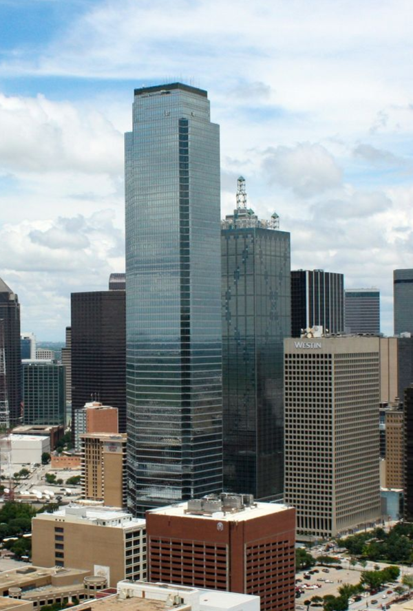 Downtown Dallas cityscape with tall, glass-faced skyscrapers under a cloudy sky.