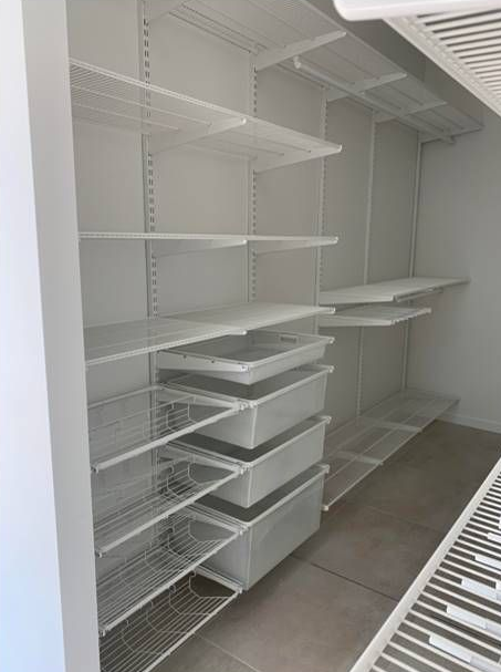 A Walk In Closet With Lots Of Shelves And A Light On The Ceiling — Roll Edge In Manunda, QLD