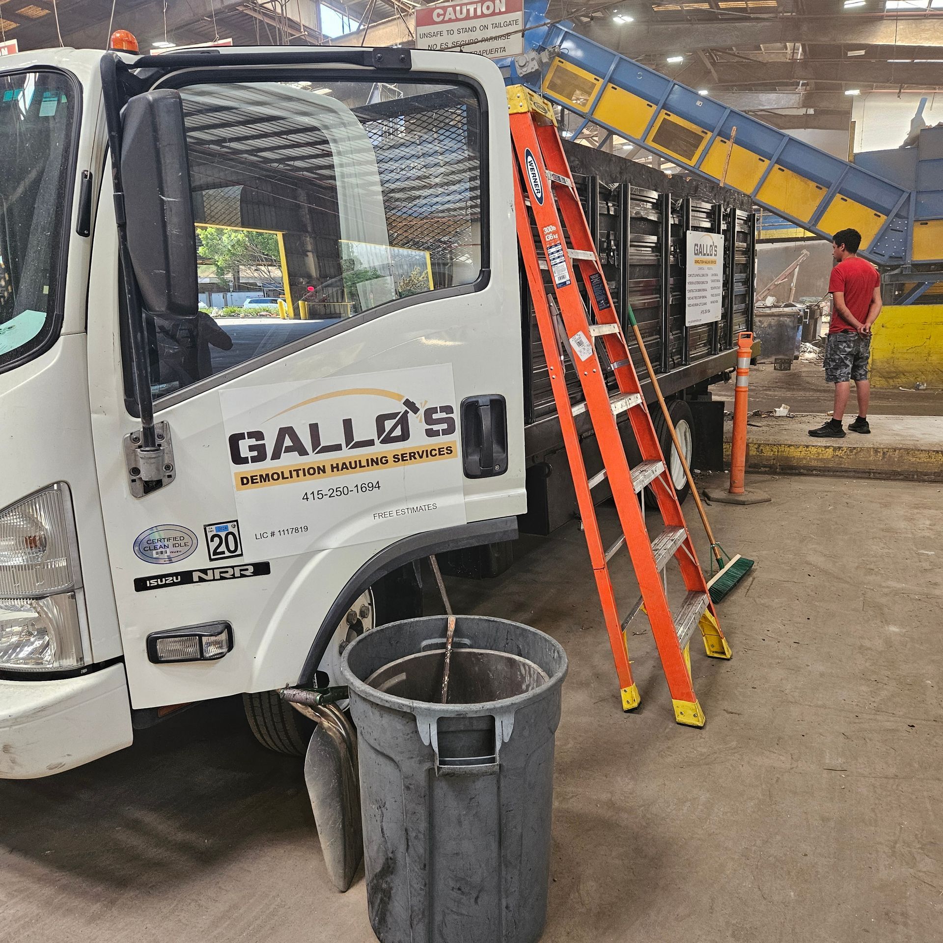 A yellow excavator is loading rocks into a dumpster.