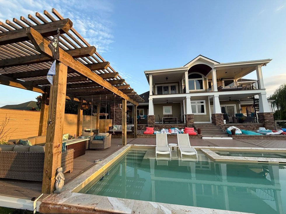 Luxury villa with pool, pergola seating, and lounge chairs under a clear blue sky