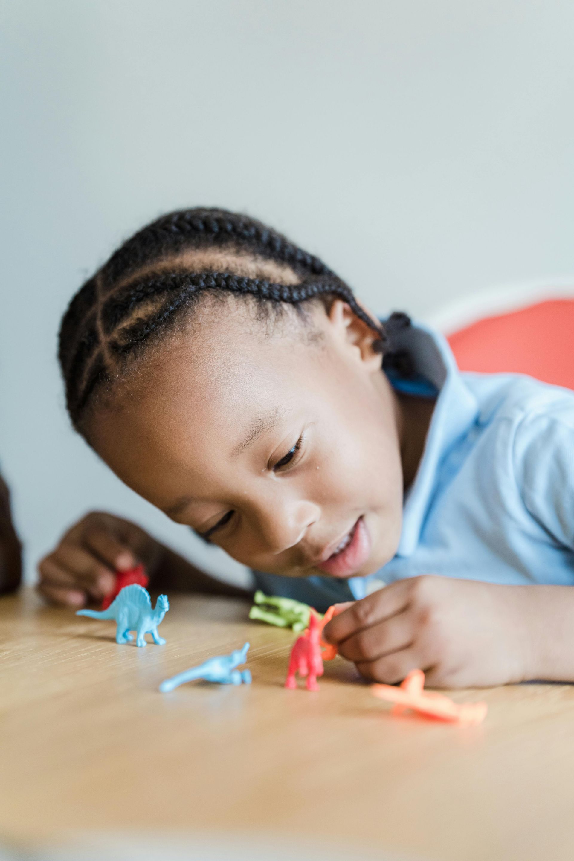 Child resting head on table while playing with colorful toy figures