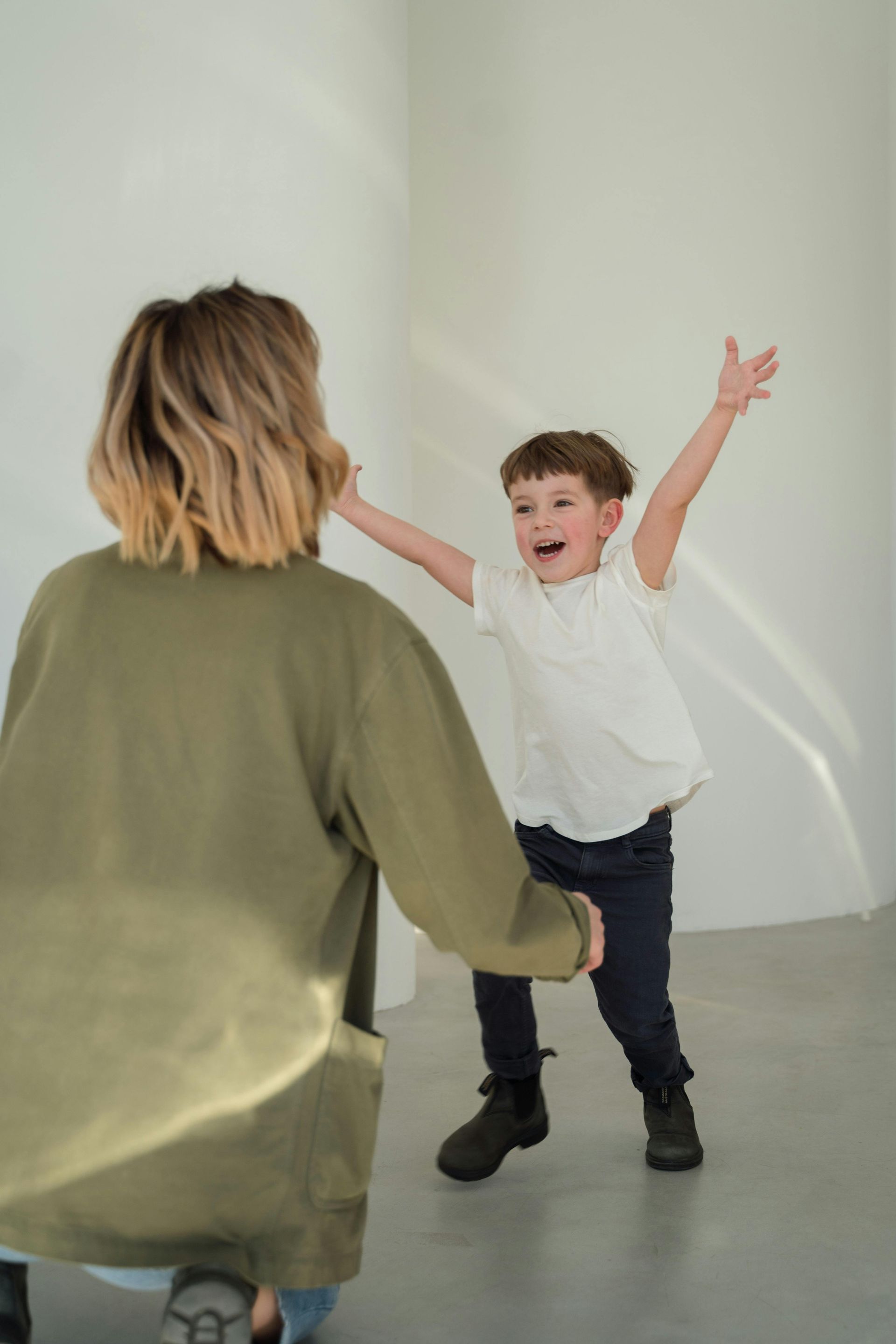 Child with arms raised toward an adult in a bright, minimalist room