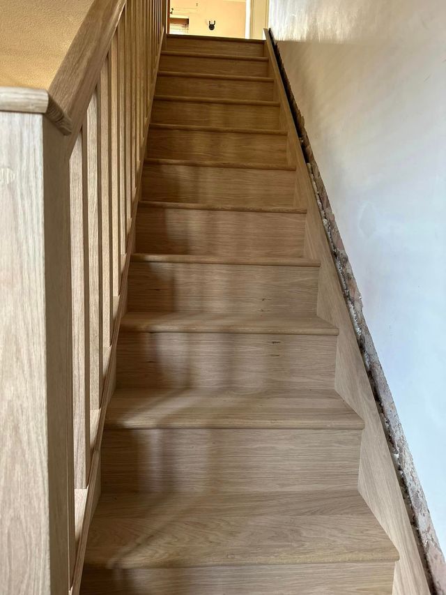 Straight flight of new oak treads and risers with an oak handrail