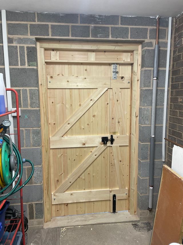 Inside of a ledged and braced timber door with a key lock, fitted in a block-built opening