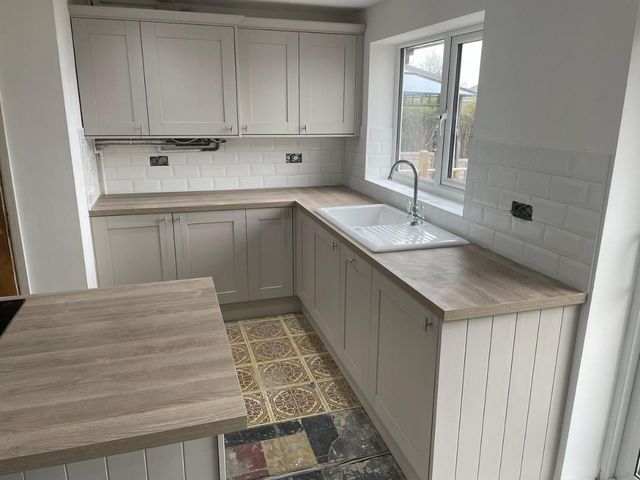 Finished kitchen with grey shaker units, oak-effect laminate worktops, a breakfast bar and a white metro tile splashback