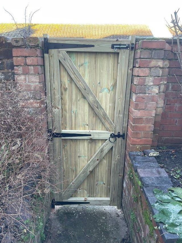 Inside face of a ledged and braced wooden gate with strap hinges and bolts