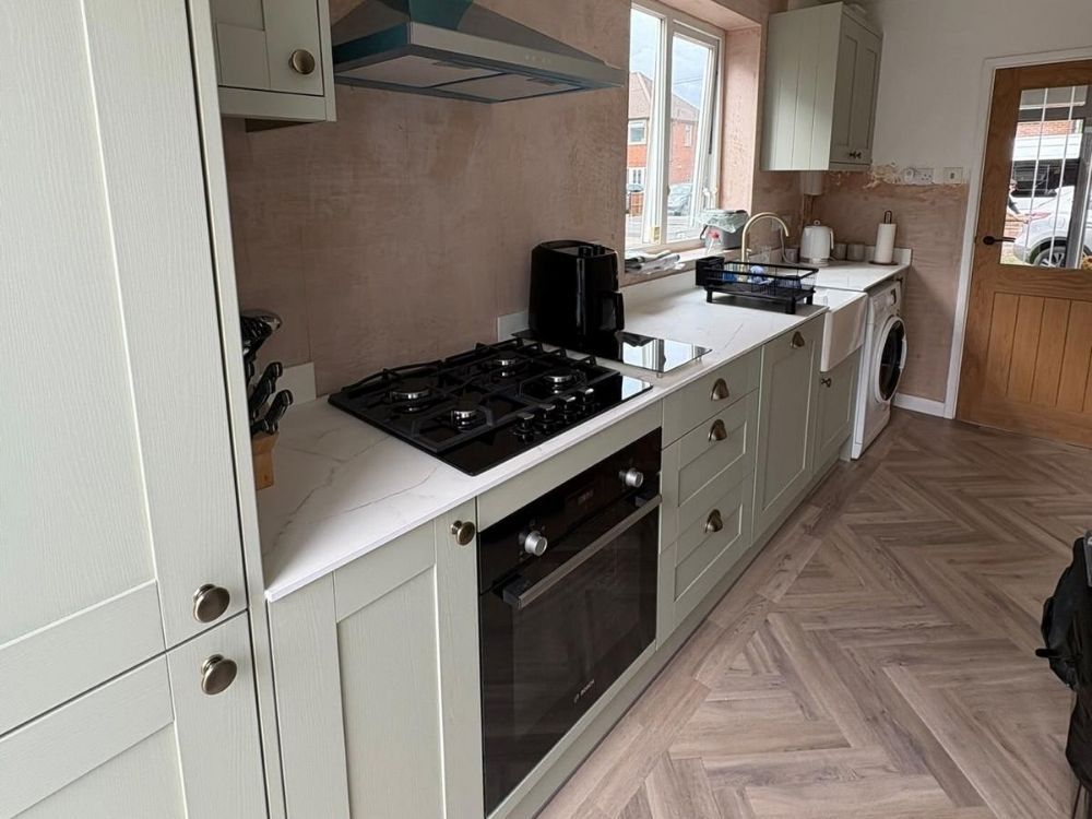 Completed kitchen installation in Alvaston with sage green shaker units, white quartz worktops, gas hob and herringbone flooring