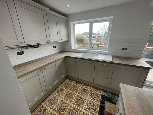 Completed kitchen with grey shaker units, oak-effect laminate worktops and a white metro tile splashback