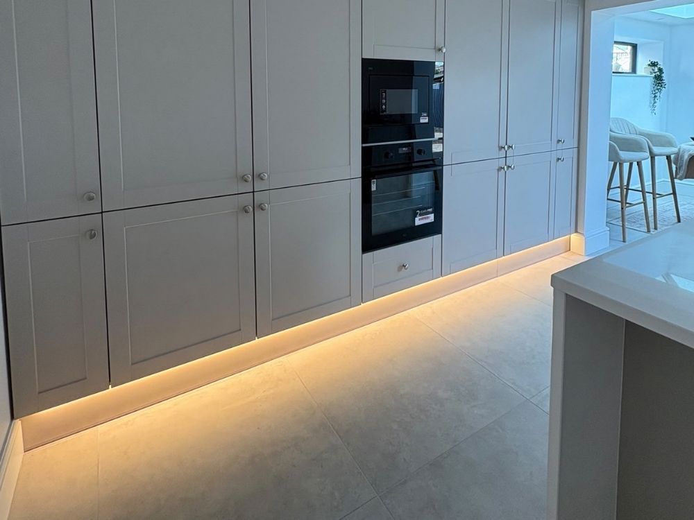 Tall larder and appliance housing in a Spondon kitchen with integrated double oven, grey shaker doors and LED plinth lighting