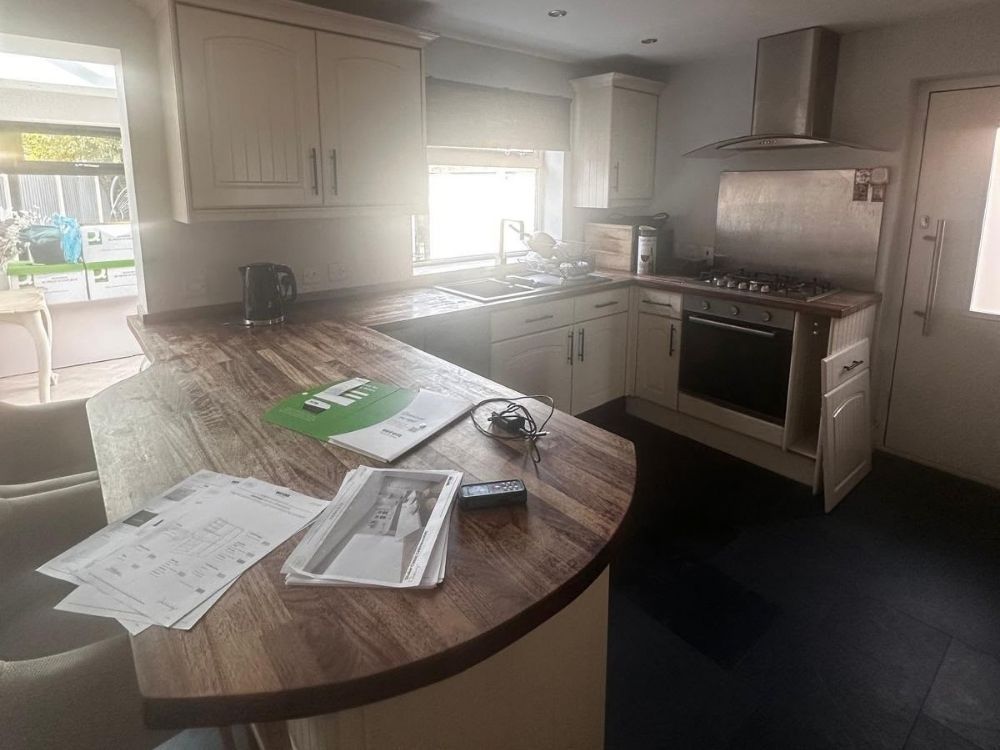 Kitchen in a Spondon home before renovation with cream shaker units, timber worktops and dark slate floor tiles