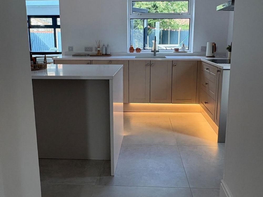 Completed Spondon kitchen showing the U-shaped run with integrated sink, island and LED plinth lighting on large format floor tiles