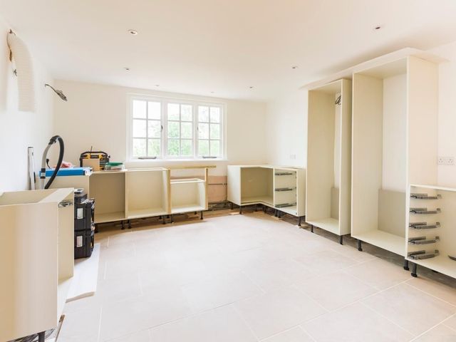 Kitchen carcasses being installed in a stripped-out room with a new tiled floor